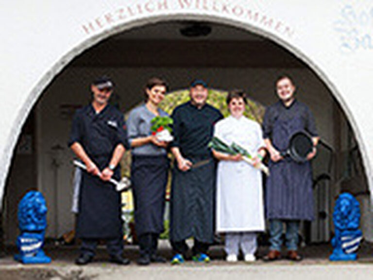 Ein Teil des Teams des Hotels Bavaria Pfronten steht in Arbeitskleidung unter einem Bogen